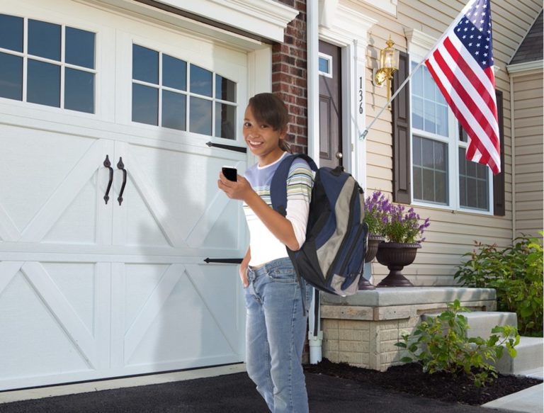 Young girl in front of Garage using her cell phone for the garage door opener