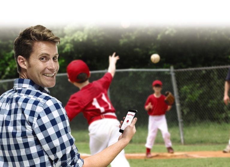 Man at a baseball game with his children using his OHD Anywhere App.
