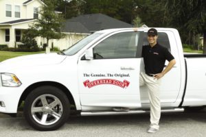 Overhead Door offers many services, including garage door installations. Overhead Door Logo Truck with a Garage Door Installer and service technician standing by his truck in a nearby neighborhood in Huntsville, Alabama serving North Alabama Since 1968