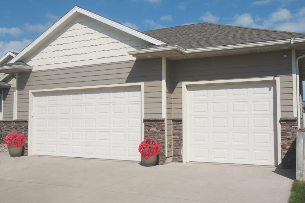 White, short panel Traditional Steel garage doors two of them on a beige house that is siding. The doors are from Overhead Door Company of Huntsville/North Alabama. 