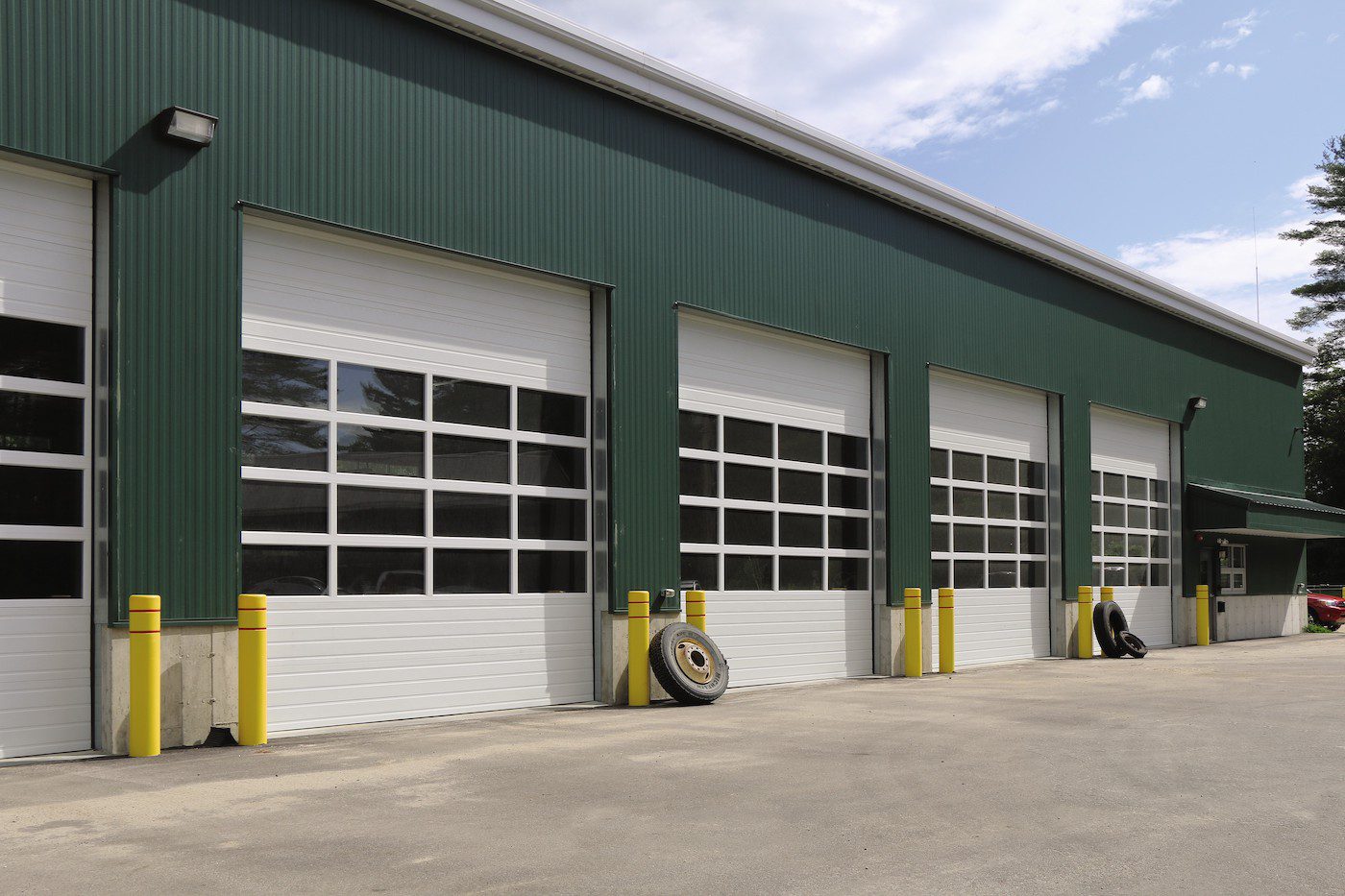 Insulated Sectional Steel-Back Doors Commercial Door from Overhead Door. 5 white doors with windows on a green building.