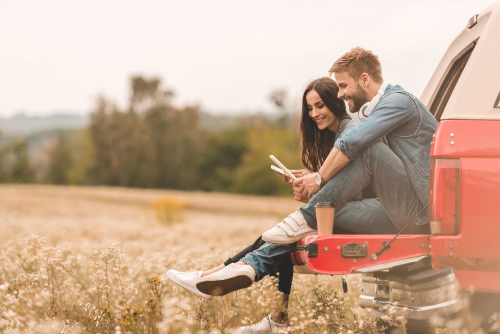 Couple on the back of a pickup truck, sitting in a cotton field, viewing their tablets trying to make a decision on buying a new garage door for their home. They are now completing the contact form located on the Overhead Door Company of Huntsville/North Alabama website.