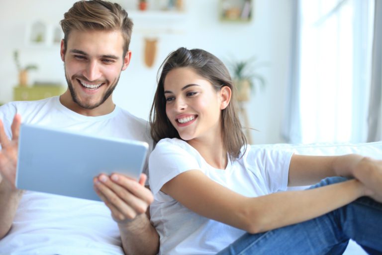 A young couple looking at tablet after choosing their new garage door after looking at the gallery on the Overhead Door Company of Huntsville website.