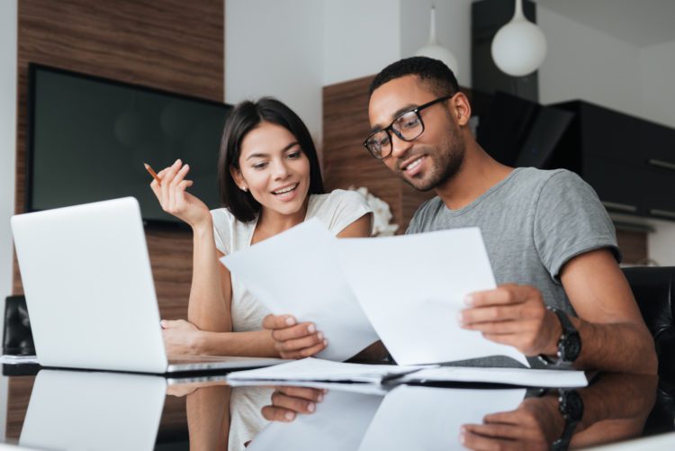 Young couple signing contract to order a new garage door and operator from Overhead Door. They are happily smiling in their den of their home.