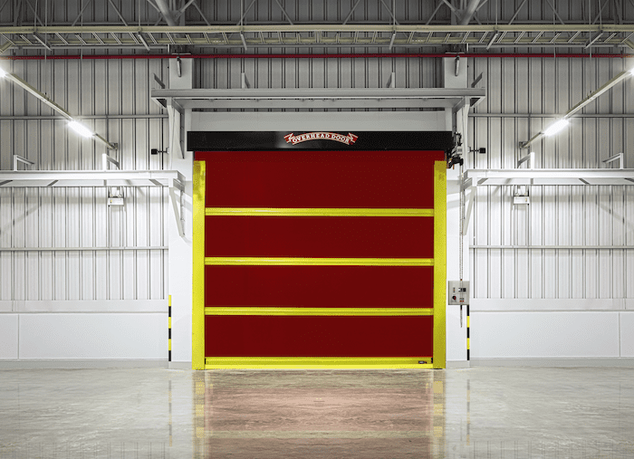 A beautiful Rapid Flex Rubber door by Overhead Door. It is bright red with yellow safety strips. The door is controlled by a Commercial operator.