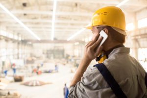 Commercial technician form Overhead Door of Huntsville talking on the phone at one of the commercial door sites. He is discussing the commercial garage door products needed for a repair to be made.