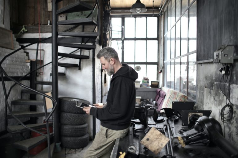 Middle aged man looking at iPad trying to decide whether to make a repair on a garage door. He is reviewing the resource page on the Overhead Door™ website for help.