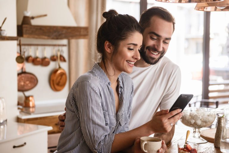 A male and female couple looking at an iPad trying to decide on a garage door Company for a service on their garage door. The couple is smiling because they see many services that are they are interested in.
