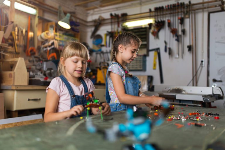 Two girls playing with their legos in their garage with their garage door open