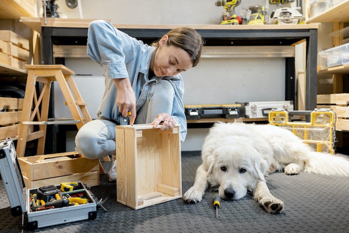 A young lady happily working in a cool garage with her white dog!