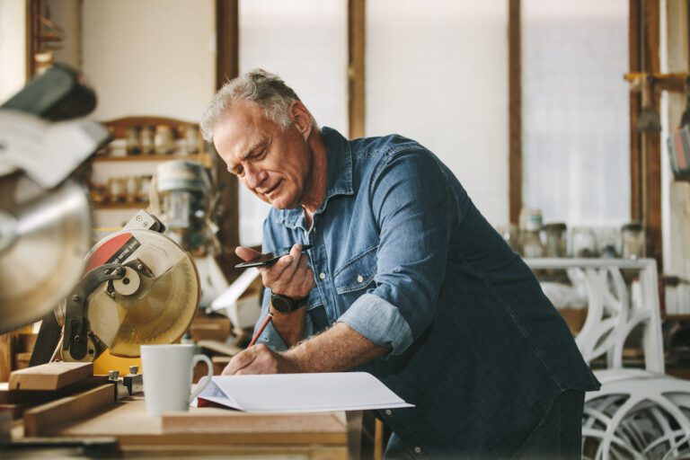 Man on a telephone taking notes while he talks to Overhead Door Company of Huntsville/North Alabama about garage door issues he is having at his home.