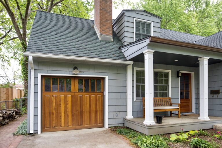 A new garage door and opener installed at a home in Hazel Green Alabama. The door is a beautiful wood garage door naturally stained from the Signature Wood Collection from Overhead Door Company of Huntsville North Alabama. The home is gray and in a wooded setting.